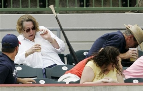 Woman dodging a flying bat at a baseball game