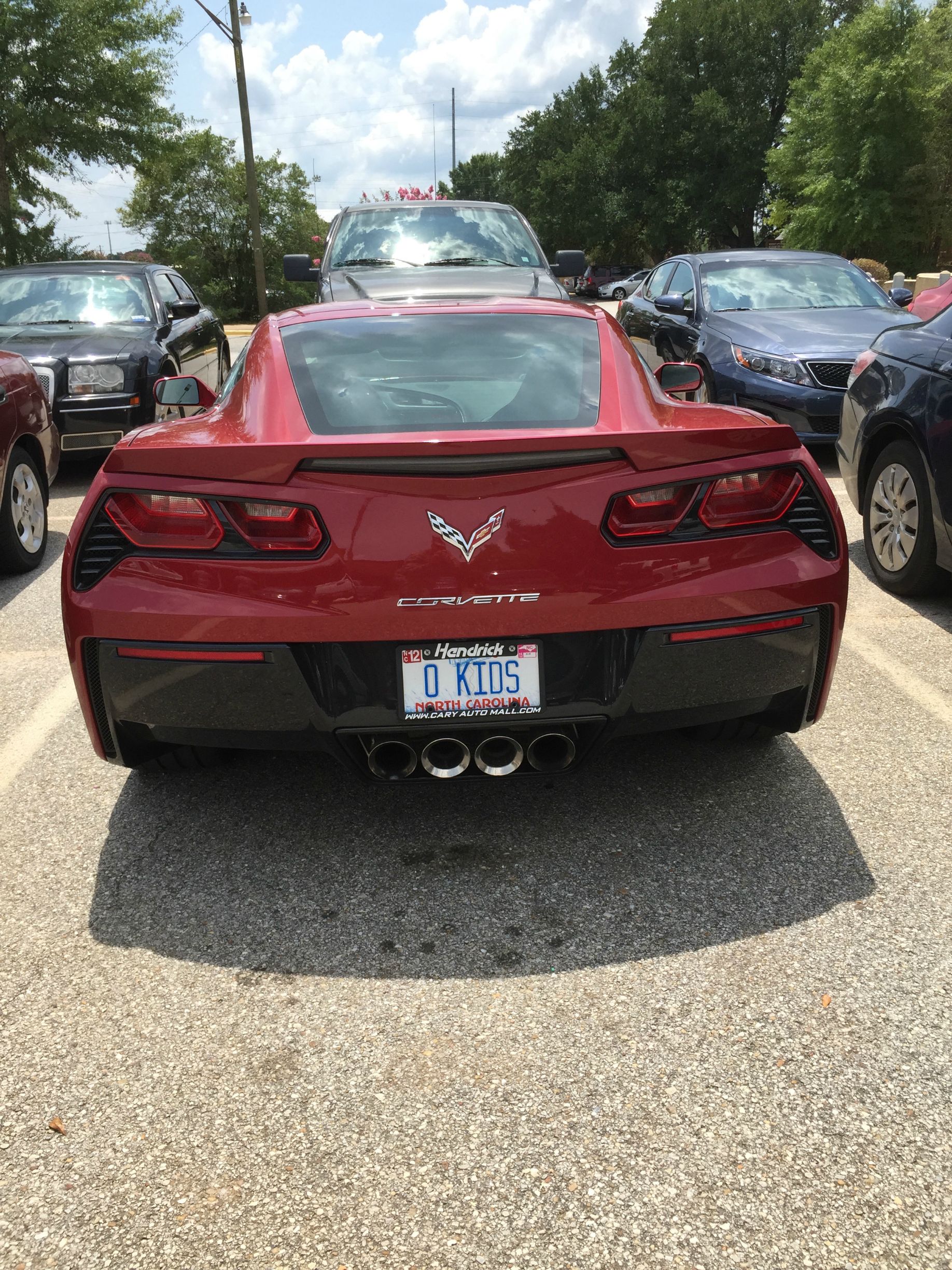 Funny picture of parked red Corvette with vanity plates that read O KIDS`