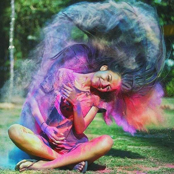 Picture of an Indian girl flipping her hair and a bunch of multi colored powders