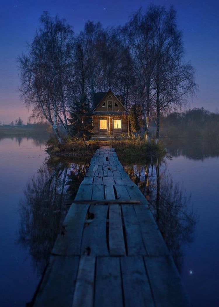 Wooden bridge across the pond to an island that has a house on it