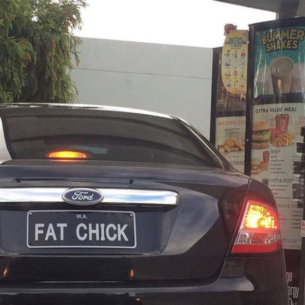 shiny black car that has a vanity license plate that says FAT CHICK