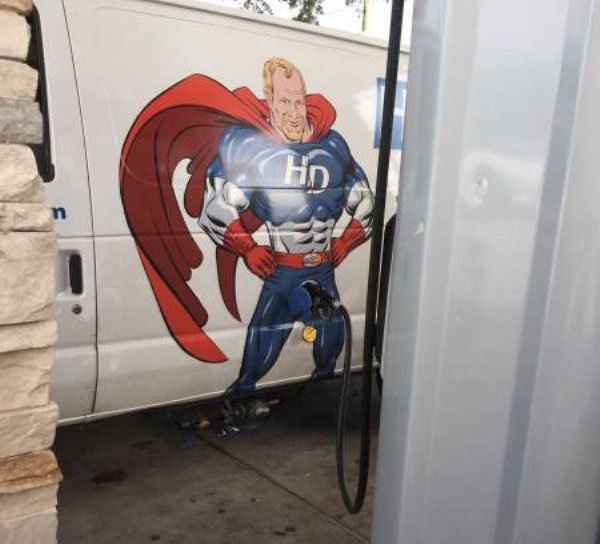 Van with superhero painted on the side with the gas nozzle being inserted into his crotch area.