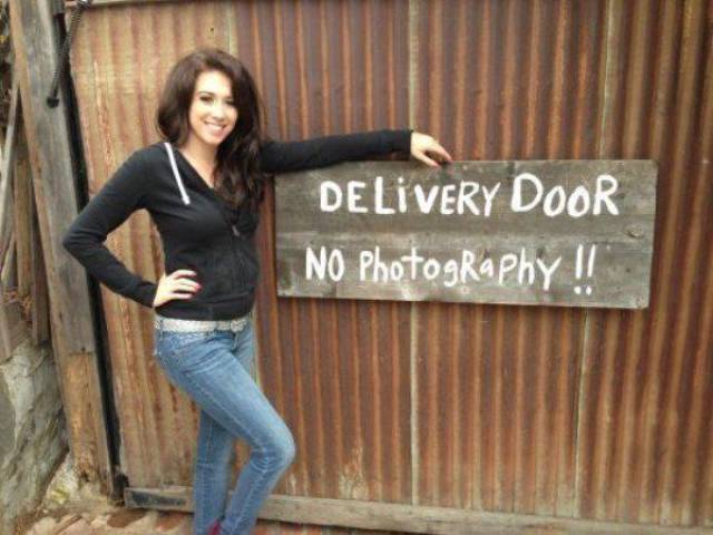Woman next to delivery door that has No Photography sign