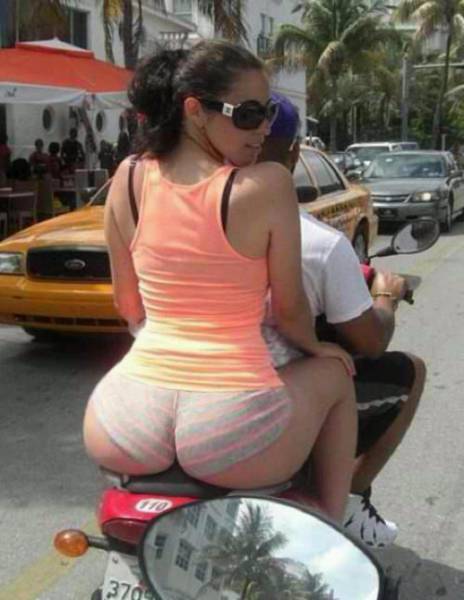 Hot woman with her butt coming out of her shorts on the back of a motorcycle.