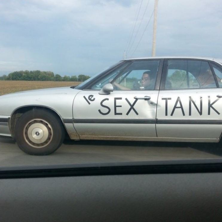 Old sedan vehicle with the words Le Sex Tank taped onto the side of the car.