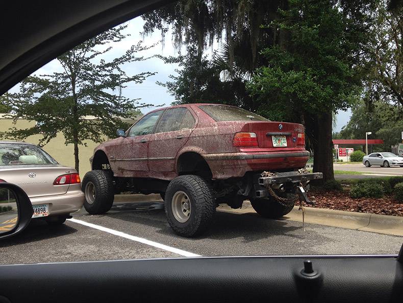 Sedan vehicle souped up with large off road tires.