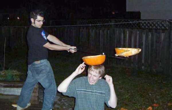 pic of man slicking pumpkin off another man's head.