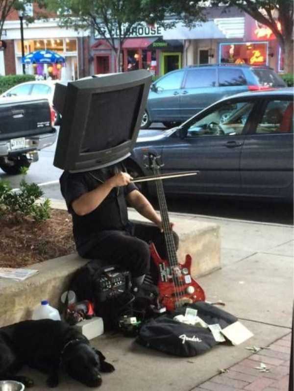 Person with TV on their head playing music in the street.