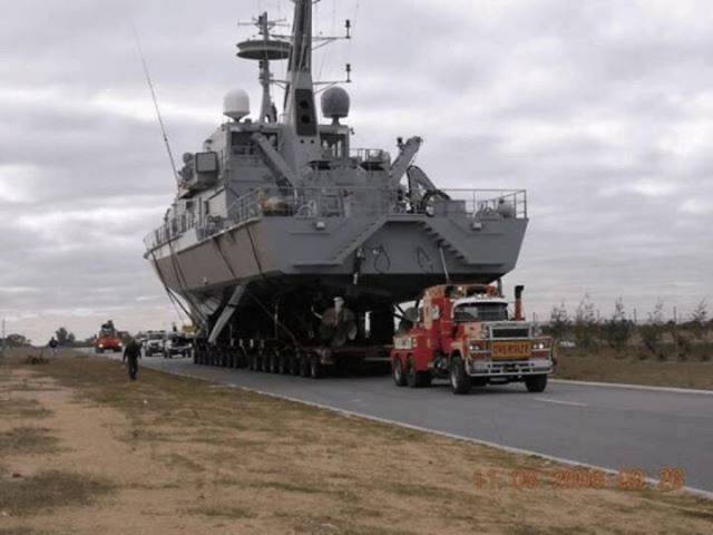 Truck pulling a frigate down the street