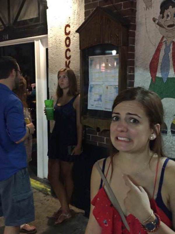 Girl making silly expression at the sign on the bar.