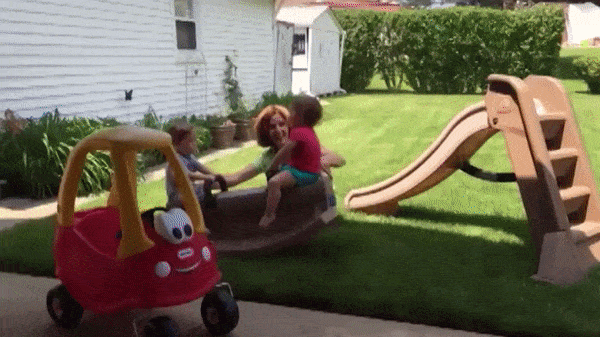 GIF of mom playing with kids and they both fall off the see-saw