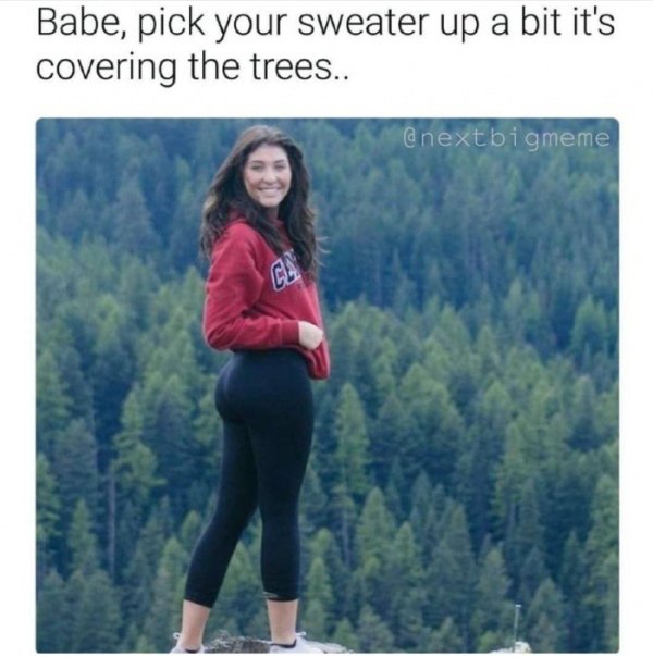 Funny pic of woman picking up her sweater in front of view of trees.