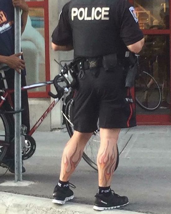 Bike cop with fire flames tattoo on his calf muscles