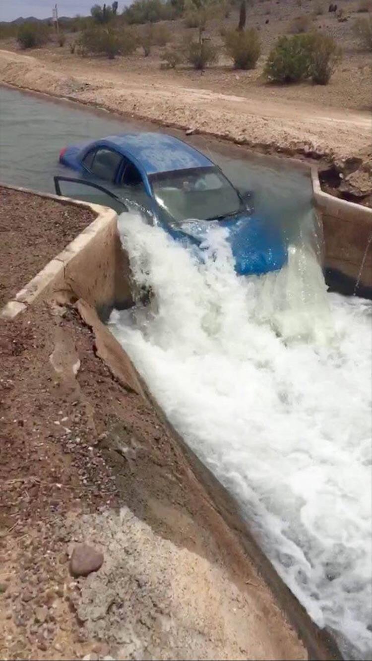 Car on a dam that has water gushing all around it