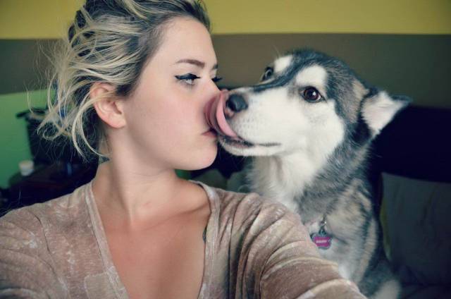 Girl kissing a dog who uses his tongue in return