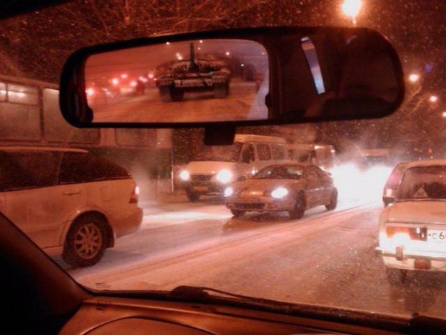 cool picture of driving through the snow with a tank in the rear view mirror