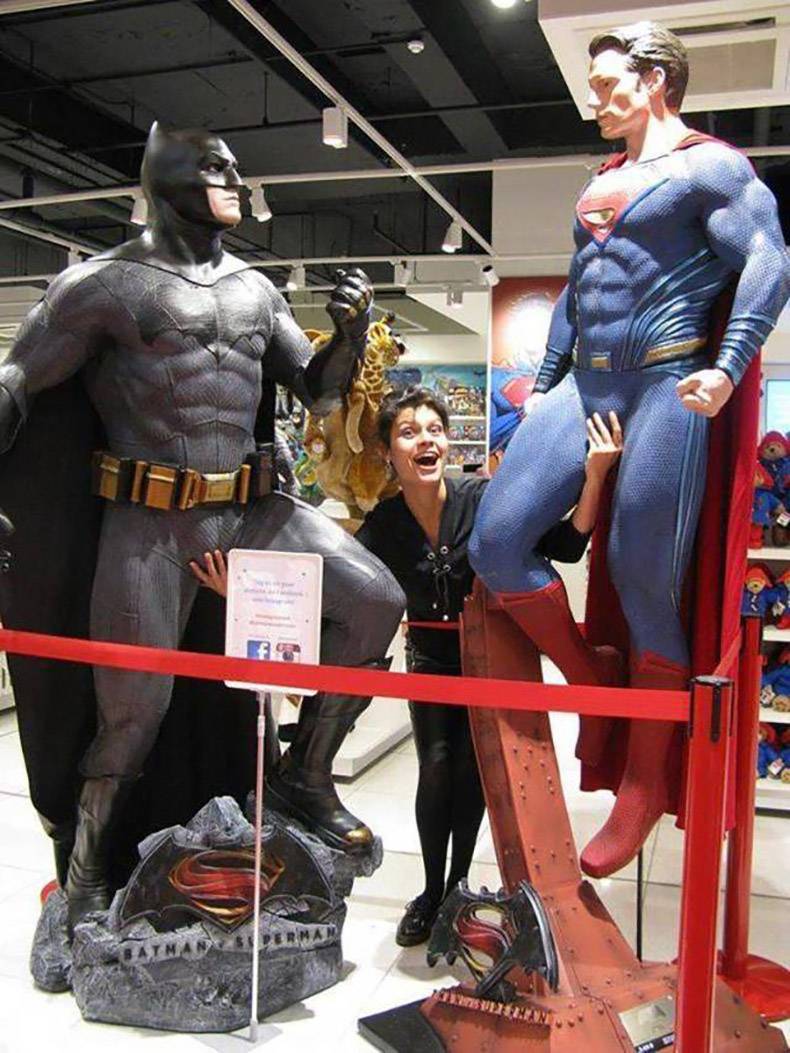 woman fondling the statues of Batman and Superman