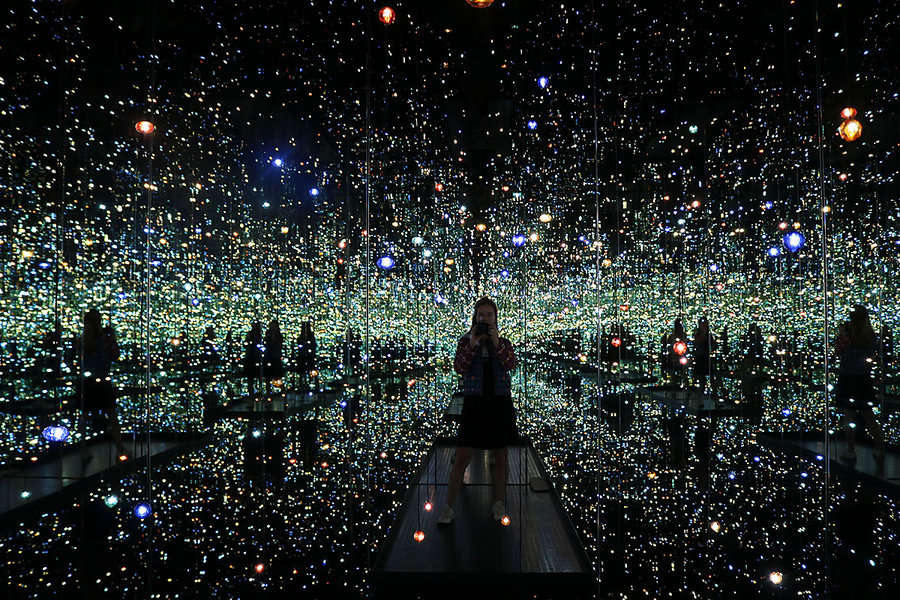 woman standing by illusion room of millions of lights