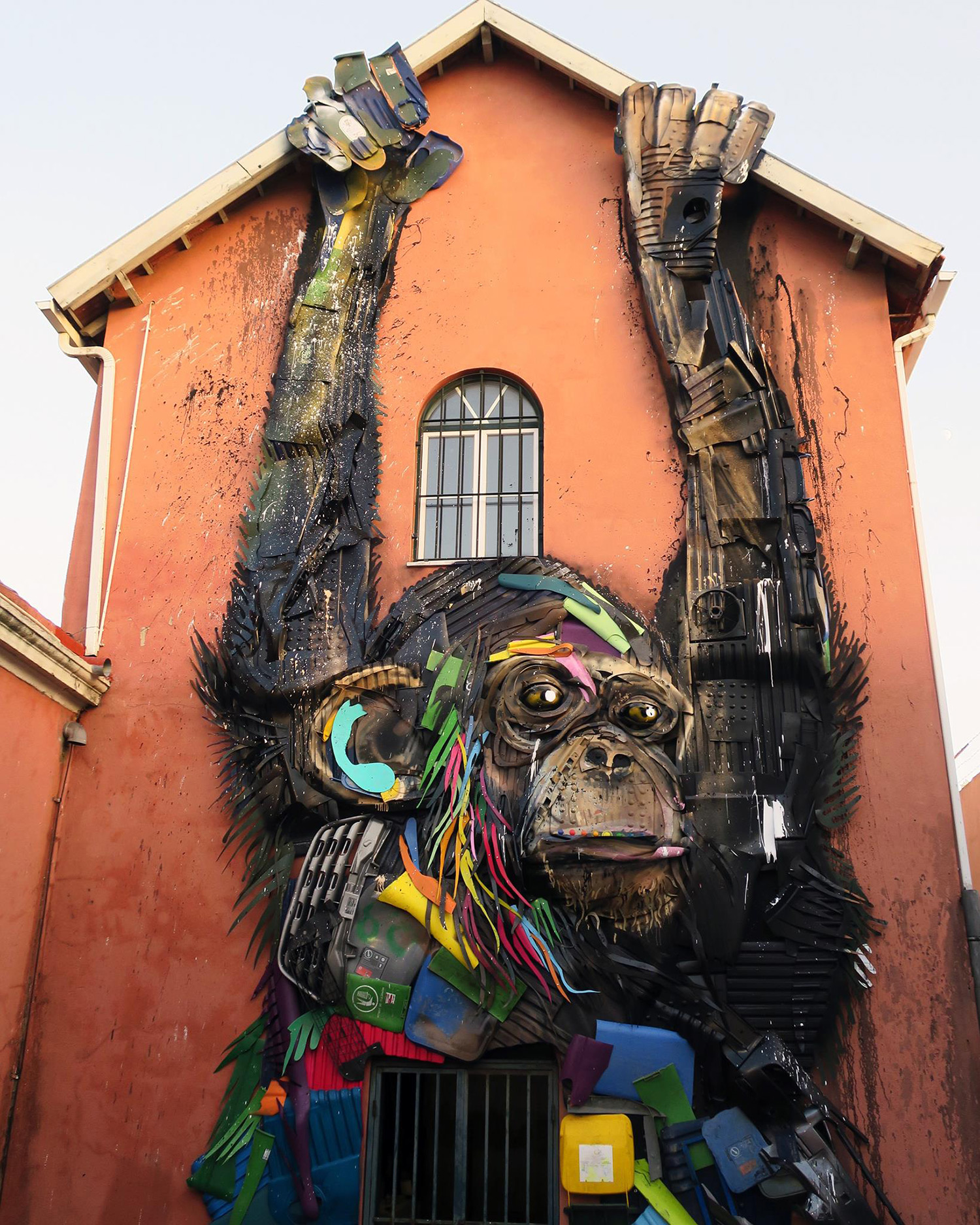 Outdoor wall art that looks like monkey climbing up that building