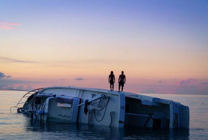 standing on the top of an overturned boat