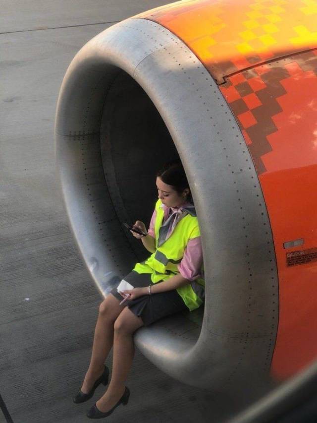 Cool pic of girl sitting in well of an airplane engine of a jet plane