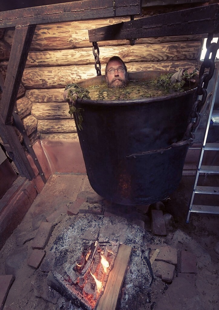 a man in a giant pot of stew above a fire