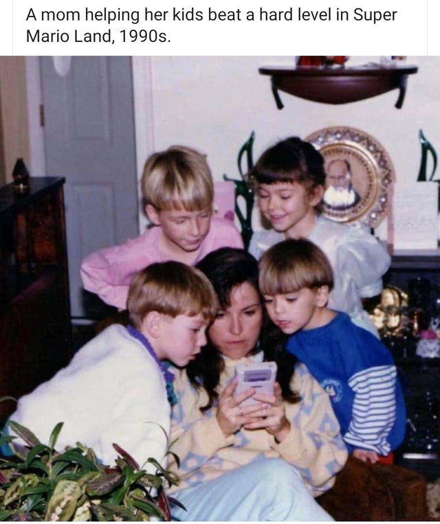 kids playing gameboy - A mom helping her kids beat a hard level in Super Mario Land, 1990s.