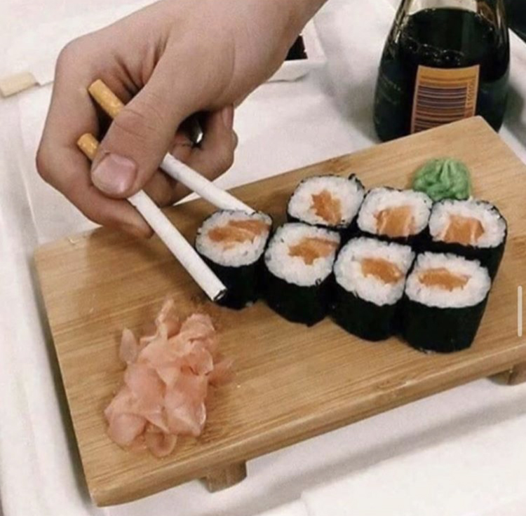 person picking up sushi pieces using cigarettes