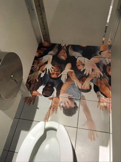 creepy unsettling image on bathroom stall floor tiles people grabbing group hands