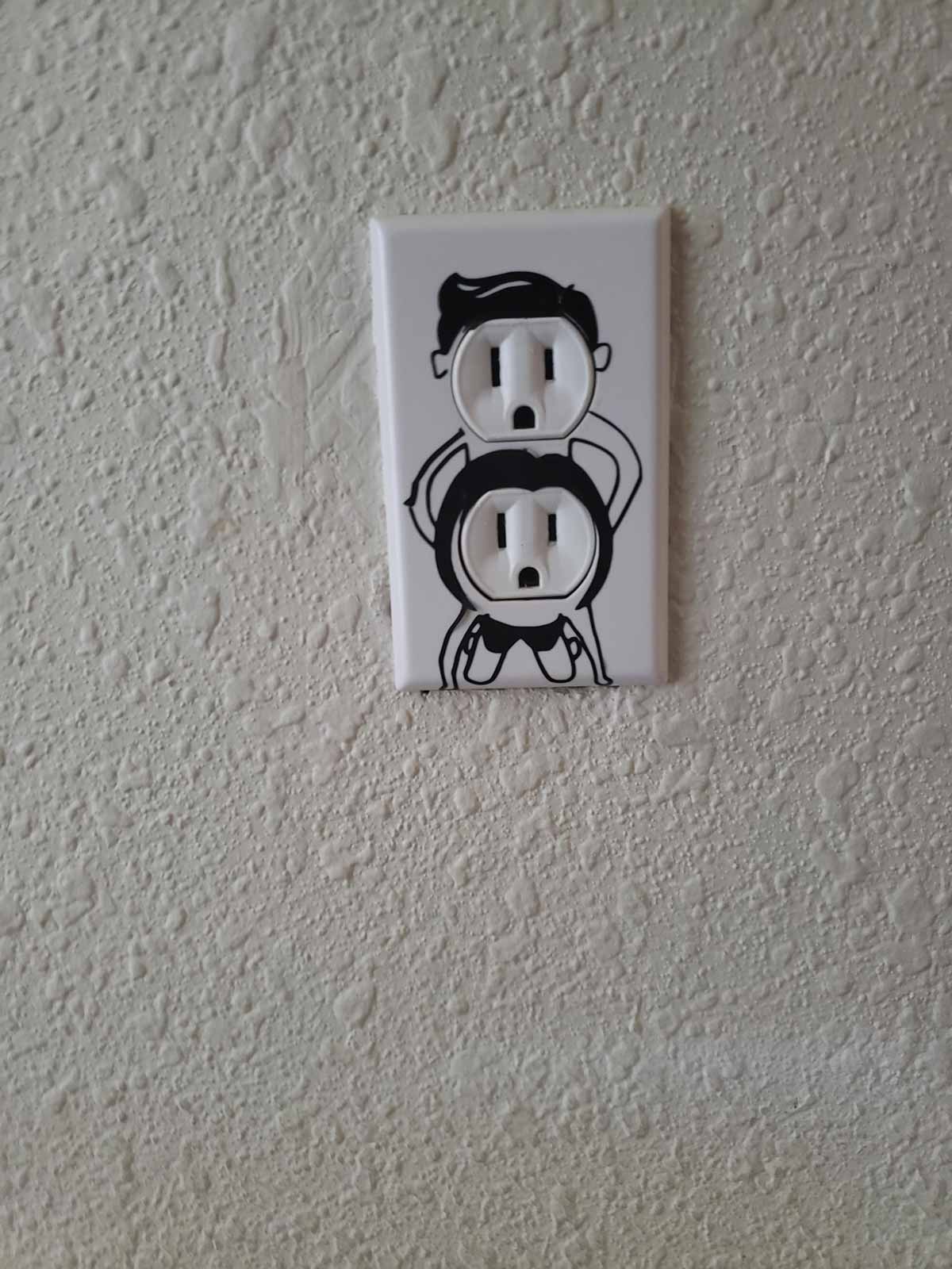 Funny electrical wall outlet where it's drawn to look like people having sex'