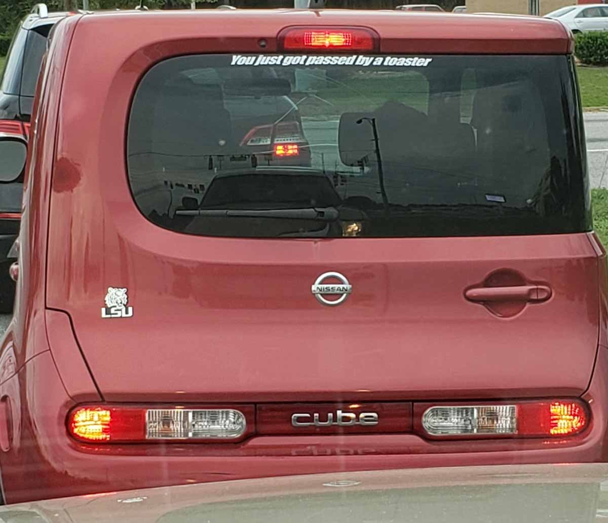 Funny sticker on the back of a Nissan Cube that says 'you just got passed by a toaster'