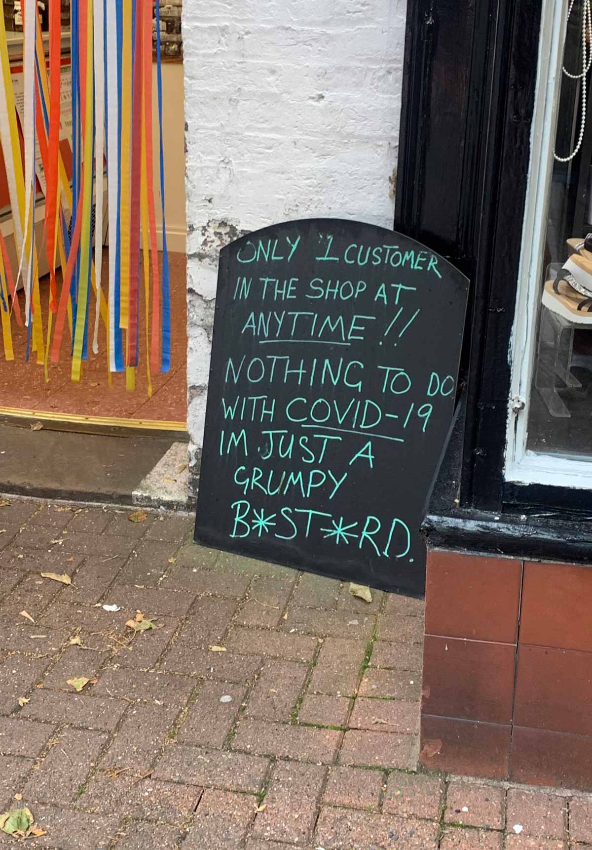 Funny photo of a sign outside of a store that says 'only 1 customer in the shop at anytime!! Nothing to do with Covid'19 I'm just a grumpy bastard'