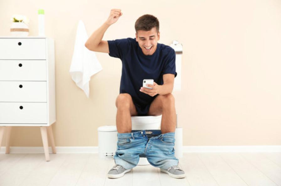 guy using phone on toilet