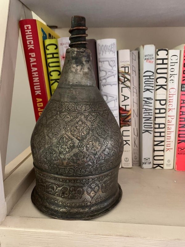 Purchased at a bazaar in Afghanistan. Hollow inside and the “cork” top doesn’t seem to come out. Made of metal. A: Well I can tell you it’s upside down, judging be the writing on the side. It’s an oil lamp.