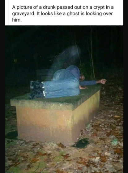 ghost photos - real ghosts - real entities - A picture of a drunk passed out on a crypt in a graveyard. It looks a ghost is looking over him.