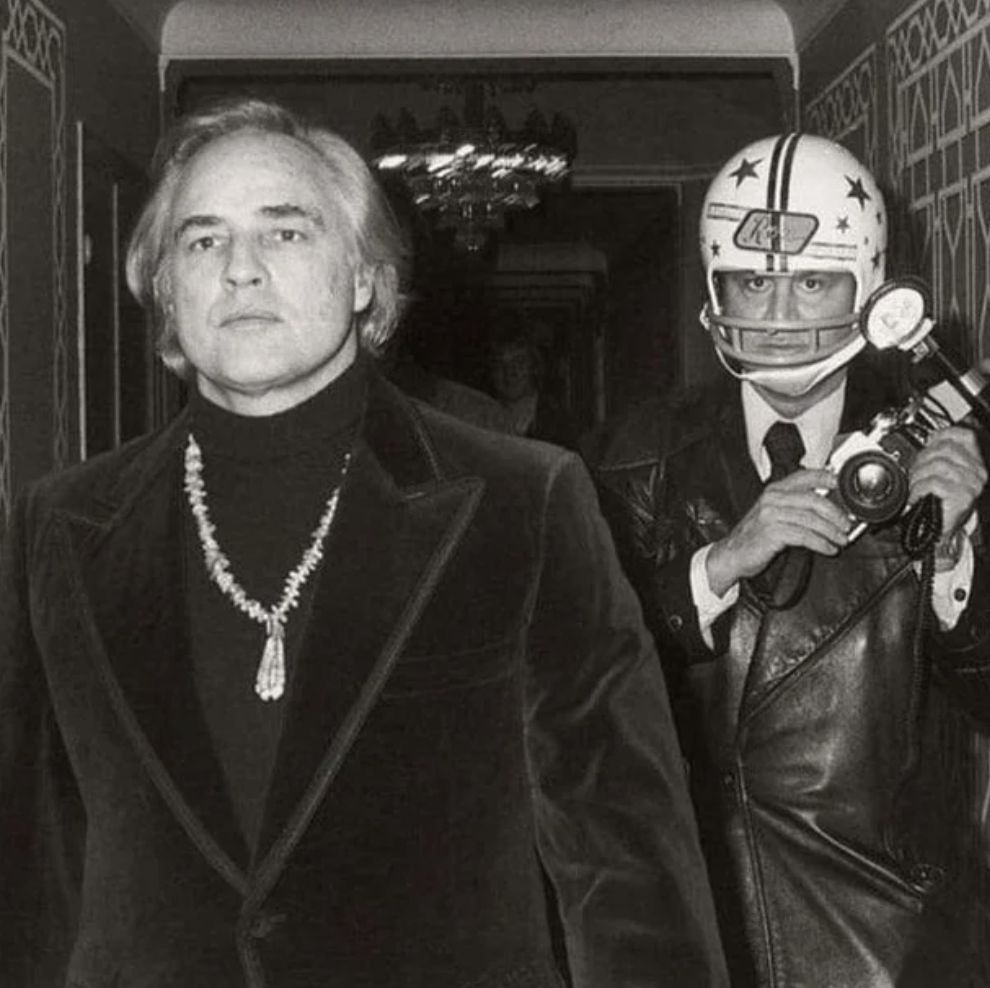 Ron Galella, a member of the paparazzi wears a football helmet to photograph Marlon Brando. Brando had previously punched him and broke his jaw.