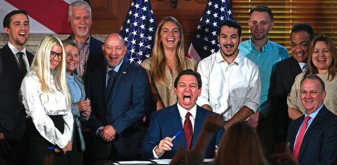 Ron DeSantis laughs after signing the bill removing funding for equity programs in Florida colleges