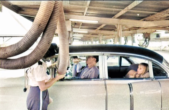 A family getting cool air pumped into their car at a drive in, 1950s