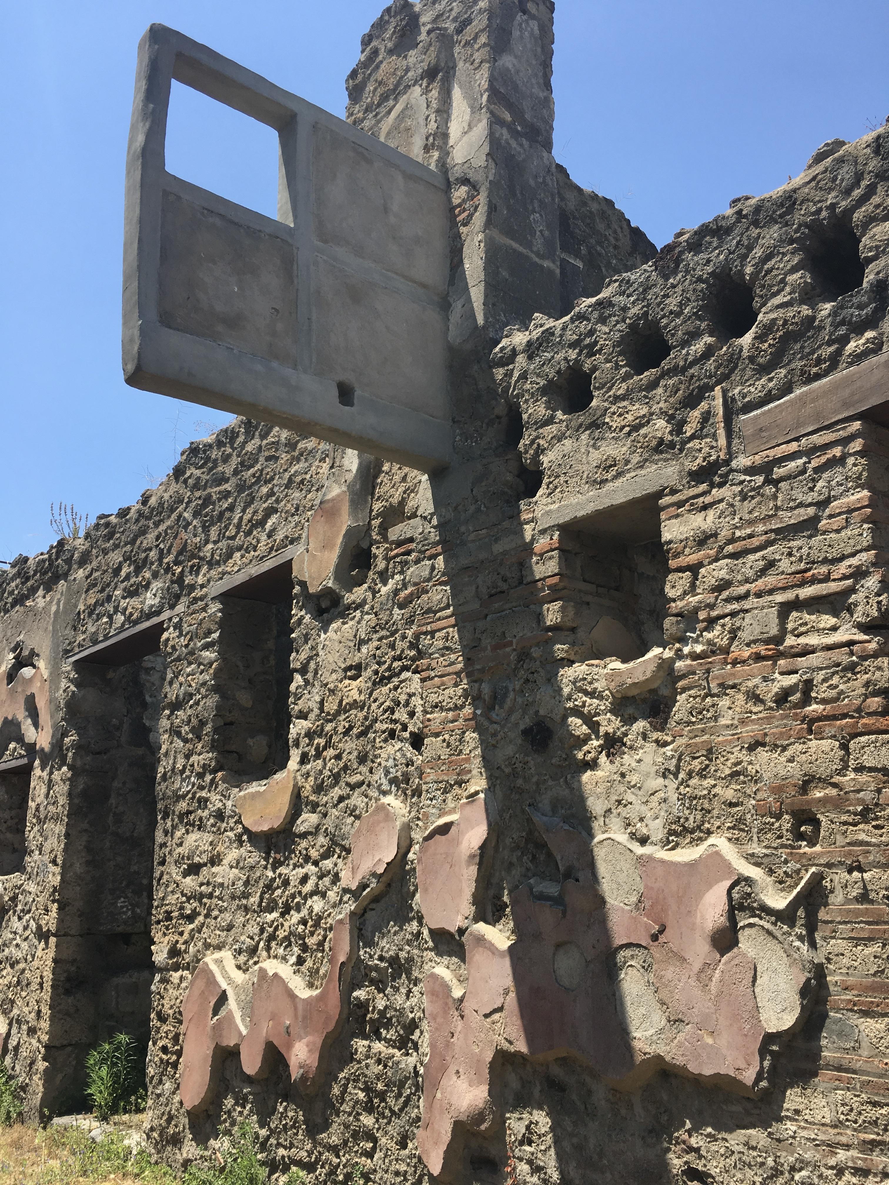 Roman "hanging balcony" partially preserved above the entrance of a 1st century CE tavern. The holes at right once housed wooden support beams. Pompeii, Italy.