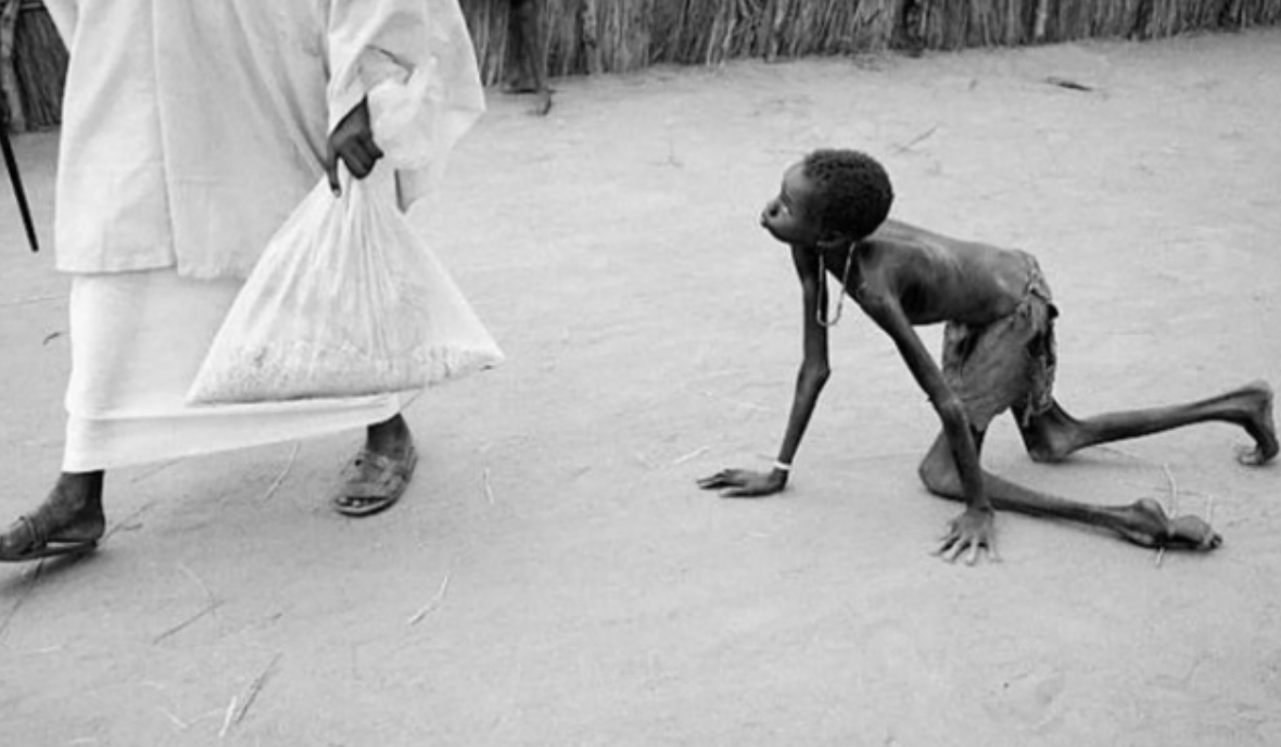 A well-nourished Sudanese man stealing a bag of maize from a starving child by Tom Stoddart.