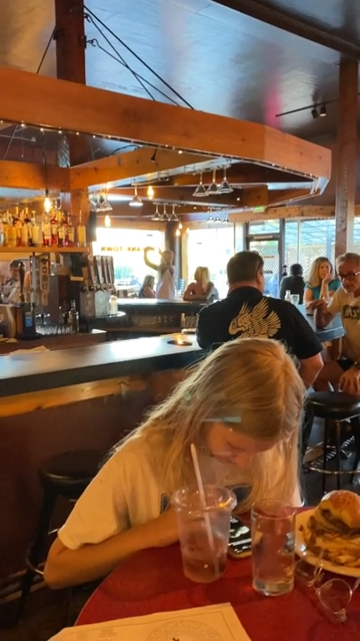 “This dingbat has made multiple laps around the bar like this, as well as taken at least ten pics of his beer. The blonde woman sitting at the bar is his date who he’s ignoring.”