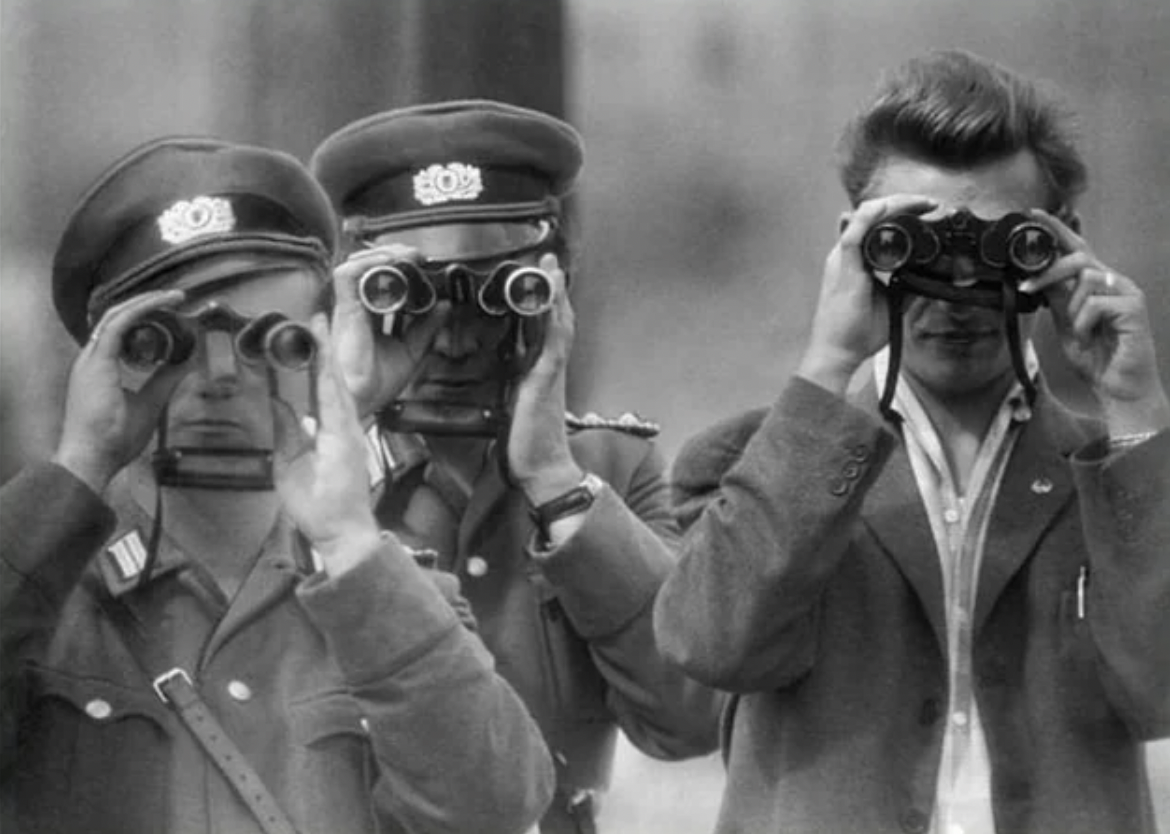 East Berlin policemen watching a photographer in West Berlin, 1961.