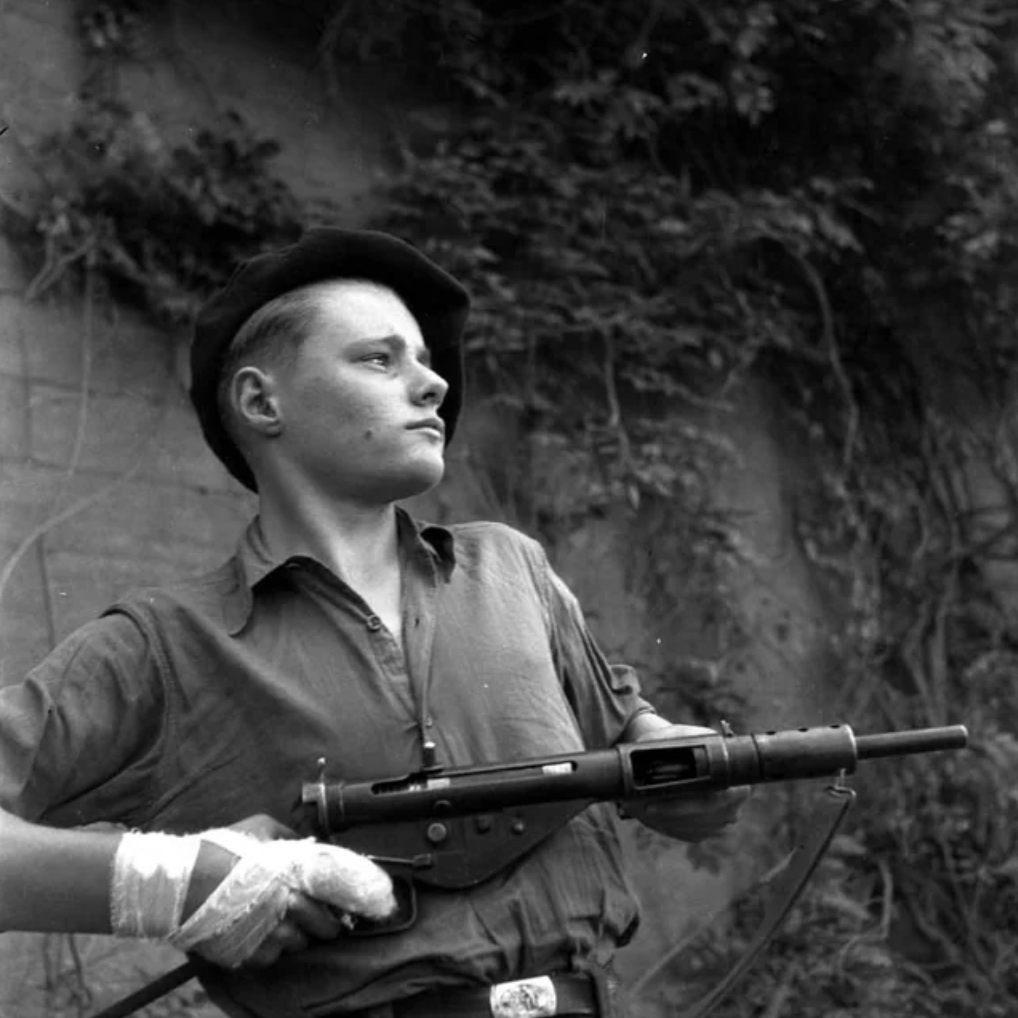 Young French resistant taking a pose with his sten, 1944.