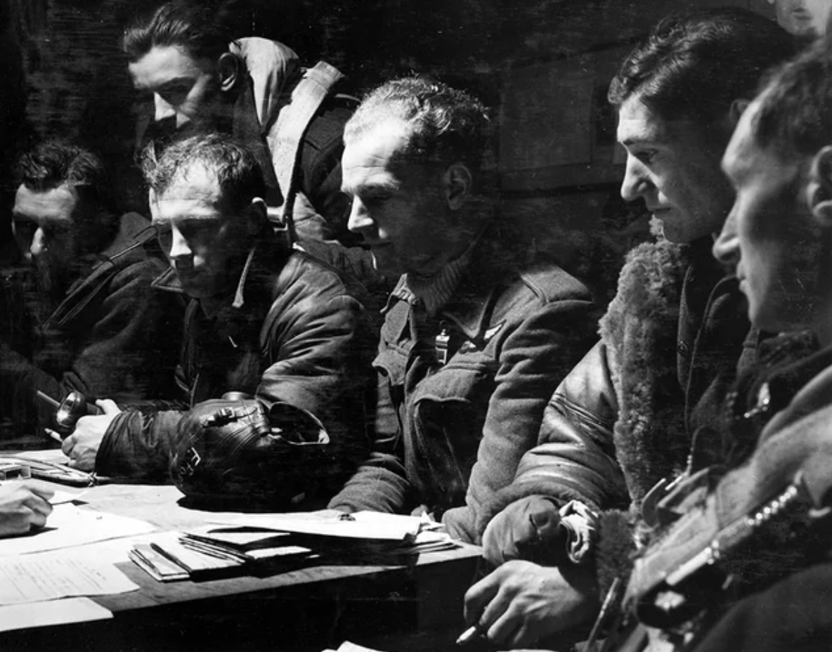 The crew of an RAF Stirling bomber undergoing debriefing by an intelligence officer after their return from a raid on Berlin. November 23, 1943.