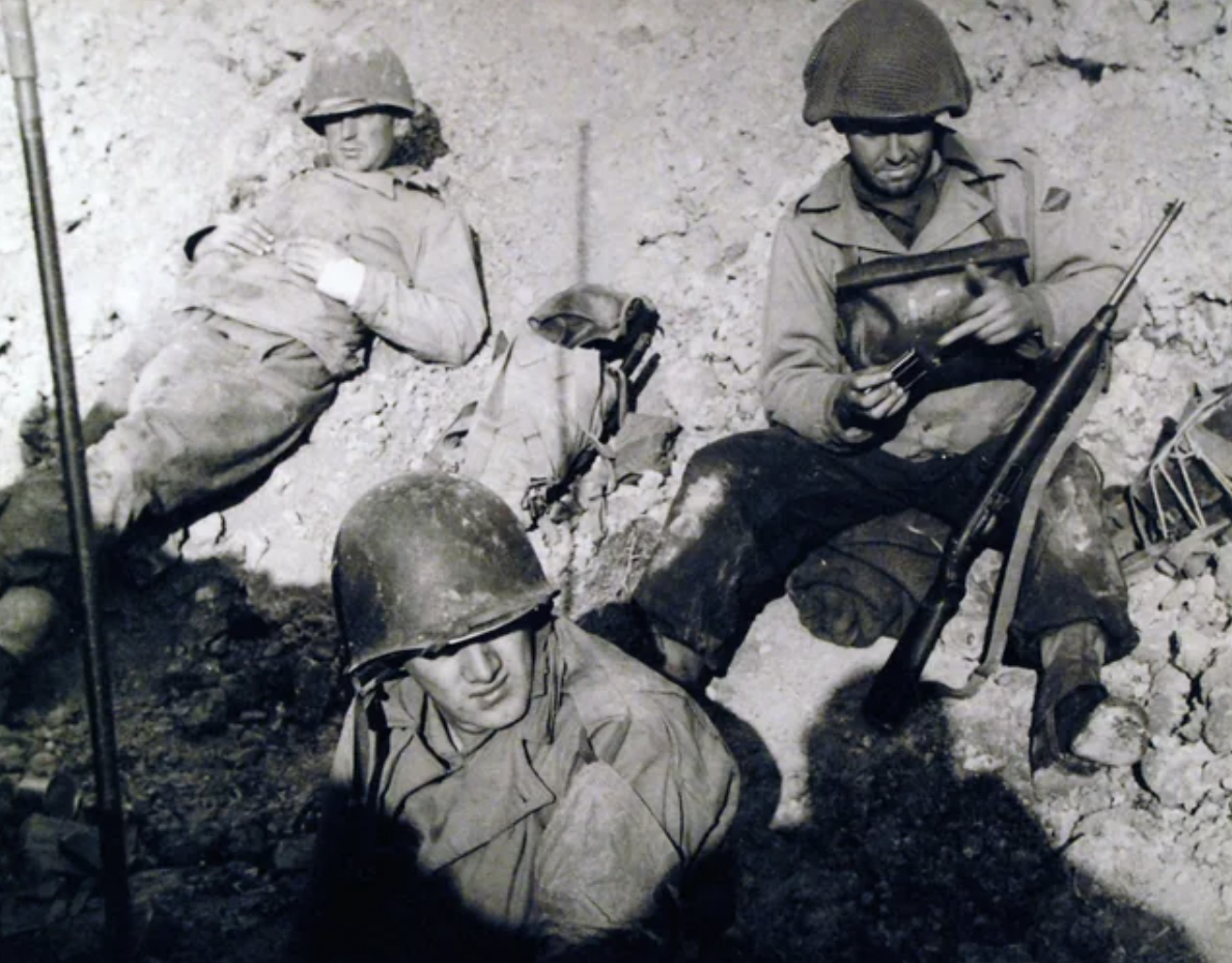 U.S. Army Rangers at work on French invasion beach, climbing high cliff to knock out German gun emplacement. Their deadly duties taken care of for the moment, the Rangers take things easy in a foxhole on D-Day. 12 June, 1944. 