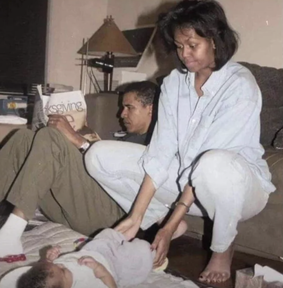 Barack and Michelle Obama in their living room with their newborn daughter Malia, 1998.