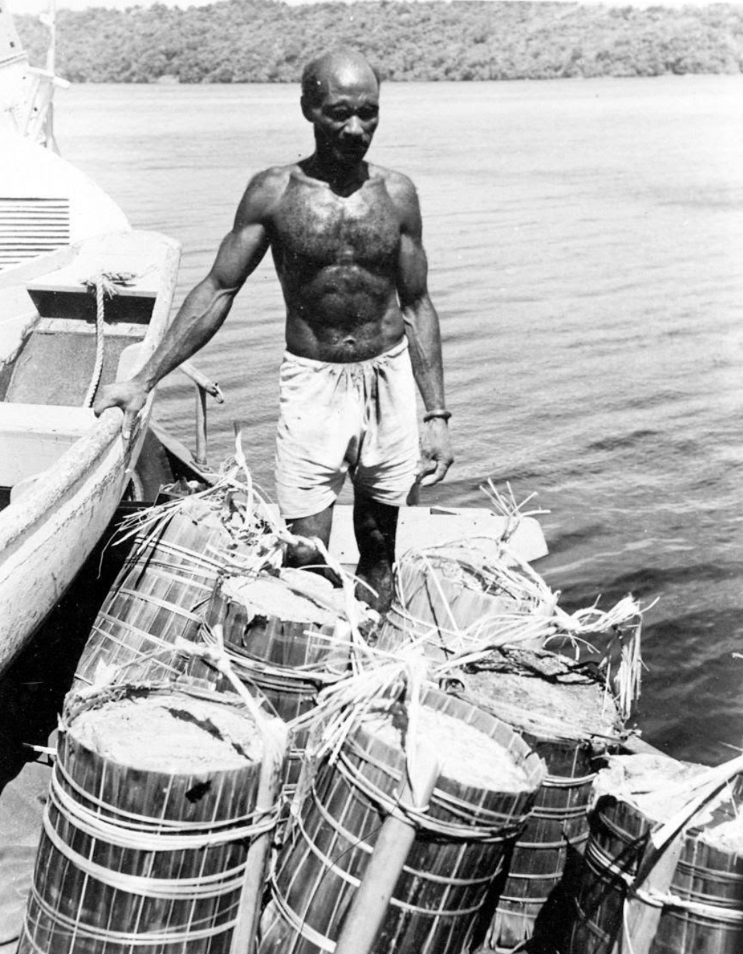 Man delivering sago flour on a boat. Papua, Indonesia, 1950-1955.