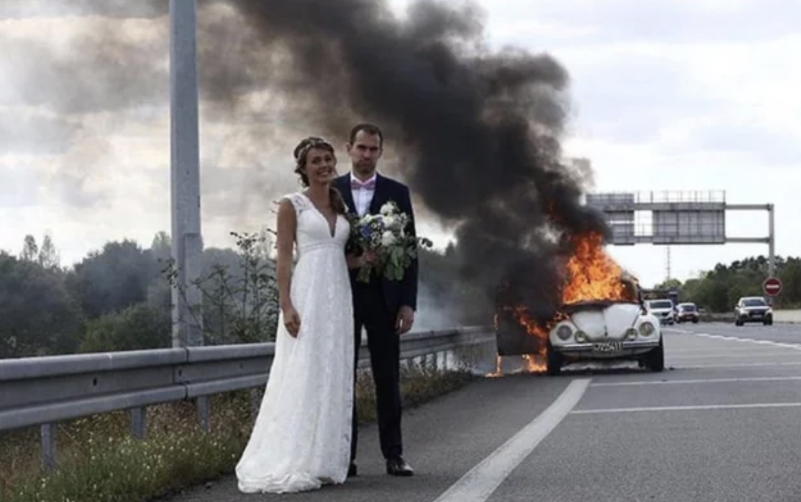 just married couple in front of their burning car