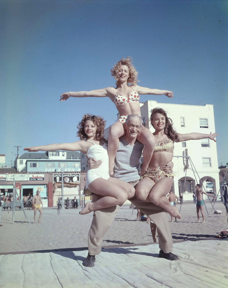 68 year old Barney Frye lifts three women, Joan Greenman, Sherry Lee Evans, Kim Curtis, on the boardwalk, Muscle Beach, 1956.