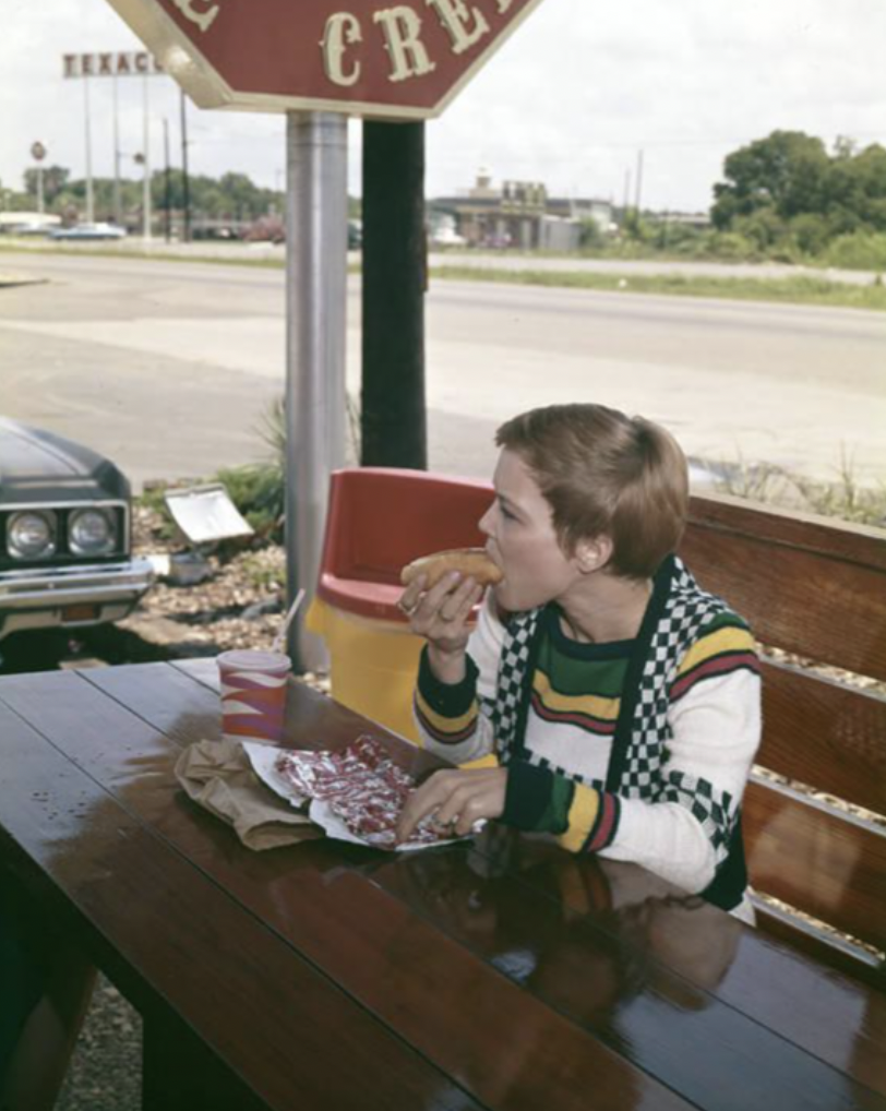 Woman eating a hot dog at a picnic table outside Casey's Caboose, a fast food restaurant in Montgomery, Alabama, June 1974.